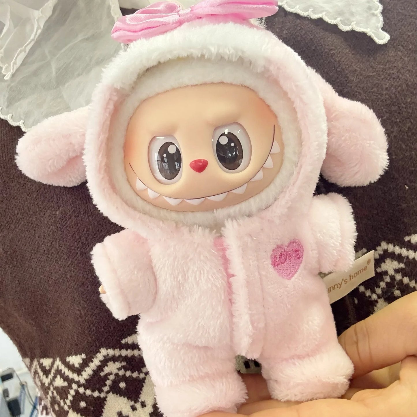Plush toy in a pink outfit with bunny ears held by a person on a patterned surface